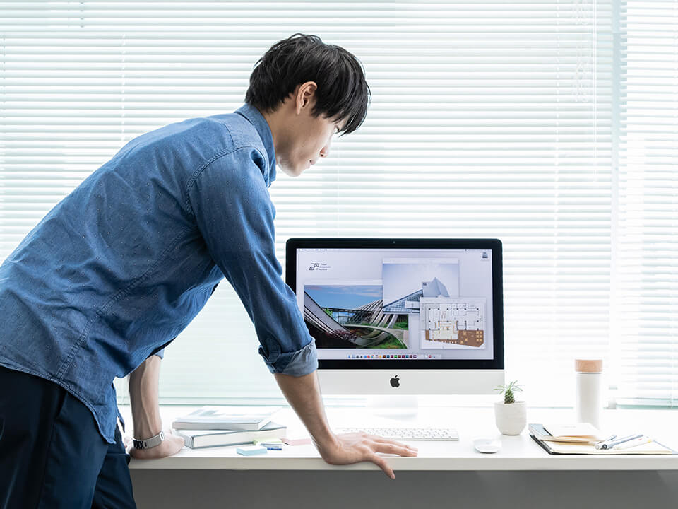 パソコン画面を確認する青い服の男性